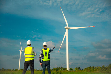Two engineer man working at windmill farm generating electricity clean energy. Wind turbine farm...