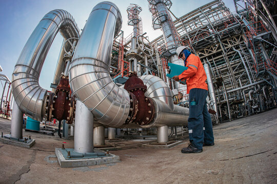 Male worker inspection at steel long pipes insulation and pipe elbow in station oil factory during refinery valve of visual check record pipeline