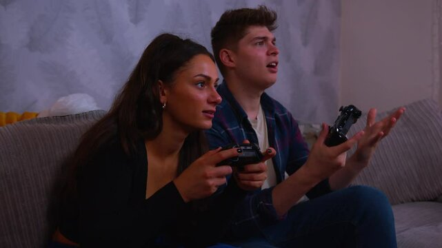Cute couple playing video games intensly girlfriend wins and celebrates boyfriend complains