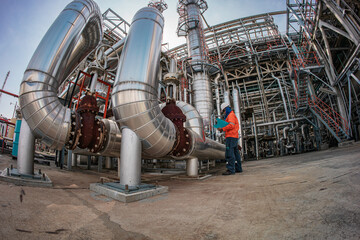 Male worker inspection at steel long pipes insulation and pipe elbow in station oil factory during...