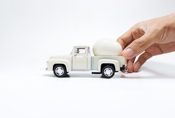 Hand holding toy car and egg isolated on white background. After edits.