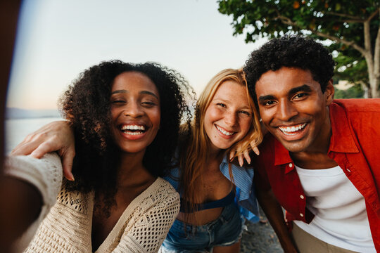 Group of cheerful friends taking a selfie at sunset outdoors - Powered by Adobe