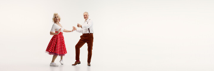 Elderly couple, dressed in vintage-inspired clothing, dances energetically retro dance isolated on...