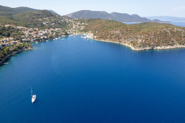 Obraz premium Sailboat sailing on deep blue sea near greek island harbor