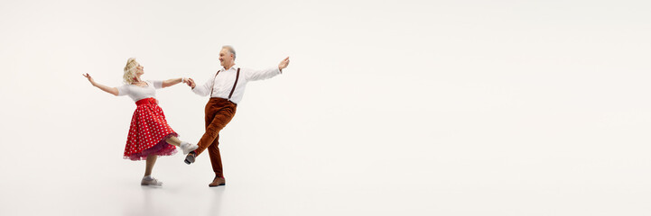 Senior couple, stylish man in suspenders and elegant woman in polka dot dress, dynamically dancing...