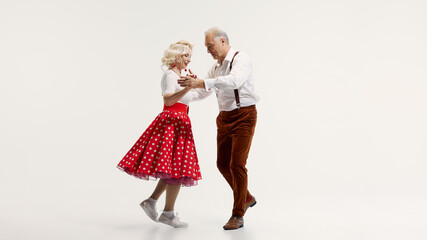 Elderly couple, woman in polka dot skirt and man with suspenders, enjoying swing dancing isolated...