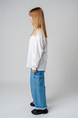 Adult female standing in casual attire with long hair, side profile captured in a minimalist studio setting