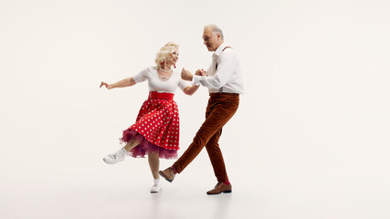 Dynamic image of elderly couple performing lindy hop dance classic moves, dressed in retro...