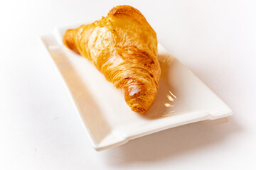 top view scene of a croissant on a white plate above white background
