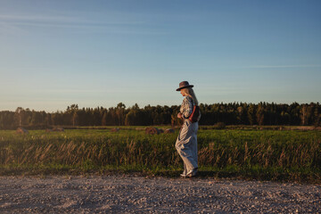 Fashionable woman walks along a gravel road in a rural setting