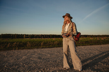 Fashionable woman with vintage photo camera on  a gravel road in a rural setting