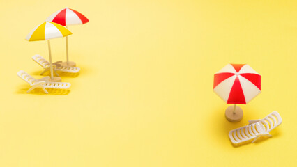 Two sun loungers and a red umbrella on a yellow background.