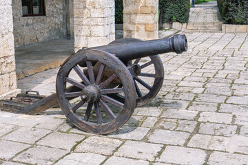 A fortress cast-iron cannon in an ancient fortress. Ancient weapons that fired cast-iron balls. Smooth bore cast iron cannon mounted on a wooden carriage.