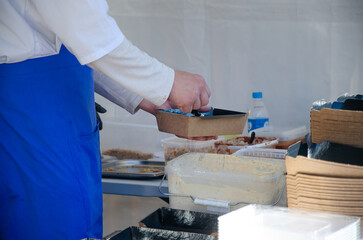 Close-up of prepared food placed in containers at an outdoor open kitchen
