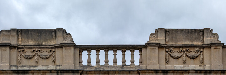Panorama of ornate stone balustrade balcony against a cloudy sky for use as a background