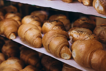Delicious croissants on the store showcase of the bakery house, close up.