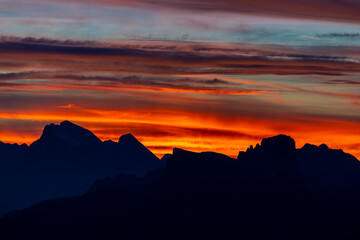 Sunset in the Dolomites beautiful landscape with mountain silhouettes and burning red light sky on the background. Sunrise and sunset in the Doloiti Alps