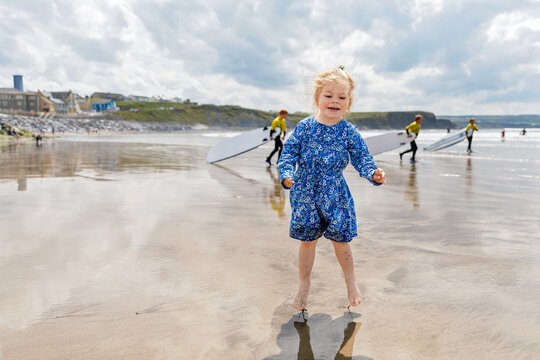 Little cute toddler girl at the Ballybunion surfer beach, having fun on with playing on west coast of Ireland. Happy child enjoying Irish summer and sunny day with family.