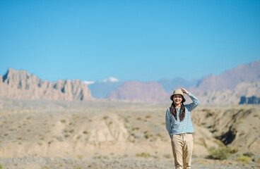 Fototapeta premium Asian female enjoying beautiful canyon landscape at Kuche Grand Canyon National Geopark, Xinjiang, China