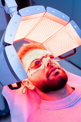 Vertical shot of a young bearded Caucasian man in his 20s and 30s undergoes low-frequency hair...