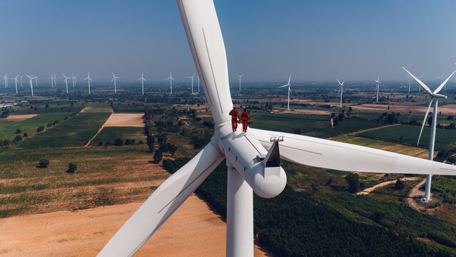 Wind mill engineer wearing PPE standing on wind turbine.. Engineering or Worker standing a top of windmill and looking beautiful Landscape.