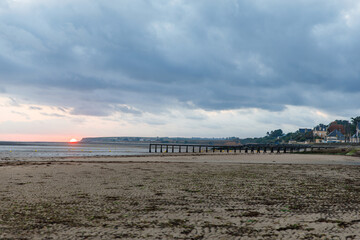Sunrise view of coastal street of Grandcamp Maisy, a scenic French coastal town in Normandy, with fishing port, sandy beaches, and maritime traditions.