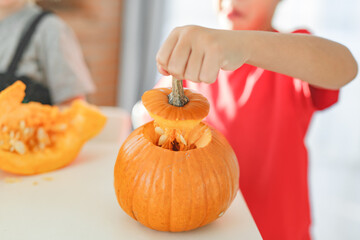 Two real happy siblings brother and sister cutting together from real natural pumpkin jack o...