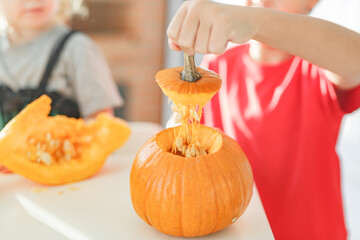 Two real happy siblings brother and sister cutting together from real natural pumpkin jack o...