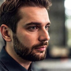 Fototapeta premium close up the worker face is illuminated by the monitor glow, sharply focused, while the rest of the room fades into a soft blur, creating a moody, focused atmosphere. Photo-realistic portrait.