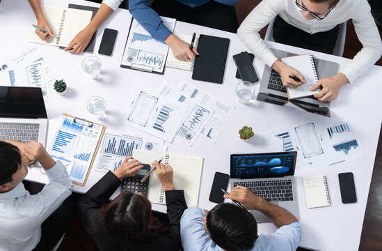 Top view analyst team utilizing BI Fintech to analyze financial data at table in meeting room. Analytic BI dashboard power on paper for business insight and strategic marketing planning. Prudent