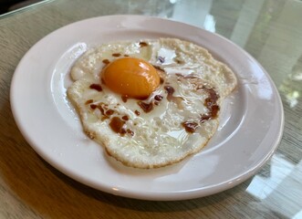 Breakfast Fried egg with soy sauce serve in white plate Served on the glass table