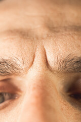 Vertical photo of a Frown lines between eyebrows on mans face. Vertical wrinkles, close up.