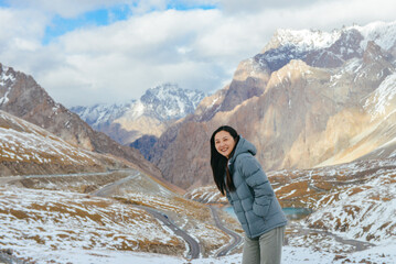 The autumn snowscape on the mountaintop of One beautiful Asian woman travels on Haxilegen Mountain along Duku Highway on the Pamir Plateau in Akto County, Xinjiang, China during September