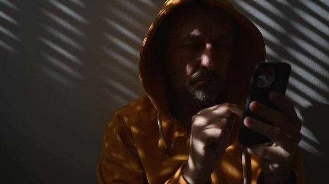 Computer hacker wearing yellow hoodie using smartphone device, 4K