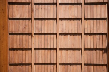 A wall made of bamboo or wooden rods. The wall is brown in color, it has a rustic feel