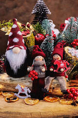 fairytale Christmas card with a gnome and toy men in knitted clothes with dried lemons, horses, Christmas tree and fir branches, New Year's entourage vertically
