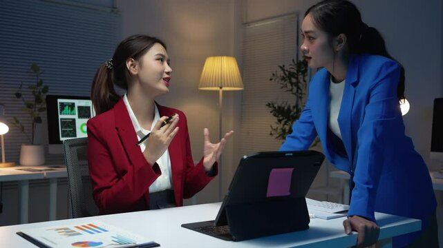 Two businesswomen working late in the office, discussing strategies and brainstorming ideas for their projects