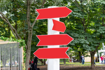 Three red arrows point opposite directions on a white pole