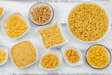 Pasta. Various kinds of uncooked pasta and noodles over wooden background