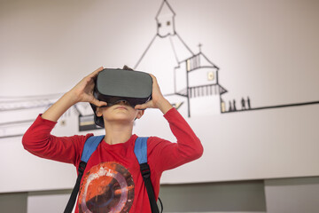 A young boy in augmented reality glasses explores an interactive museum exhibit, merging technology...