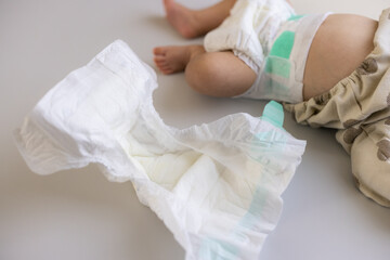 Baby changed diaper lying on mat with dirty diaper beside