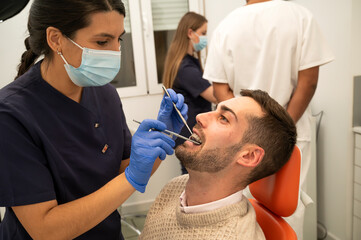 Female dentist performing a dental check-up on a male patient