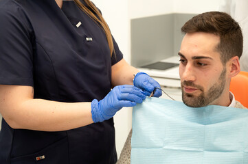 Dental assistant preparing the patient with a protective bib before the procedure
