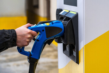 Hand Plugging Electric Car Charger into Station