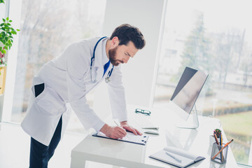 Obraz premium Photo of serious expert doctor guy stand write clipboard in hospital interior