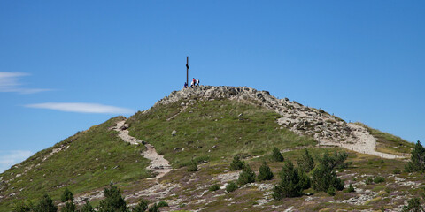 Fototapeta premium Touristes au sommet au pied de la croix du Mont Mézenc sommet de l'Ardèche et de la Haute-Loire