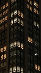 Obraz premium Seamless pattern of illuminated windows on tall building facade at night, building