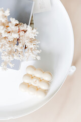 White cozy home concept. Burning candle light, coral, white table, books. Copy space