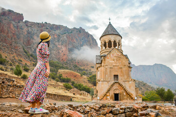 Pretty carefree Tourist woman stand on viewpoint admires view famous Armenian monastery of Noravank. Travel and tourism concept. Top popular travel explore destination caucasus