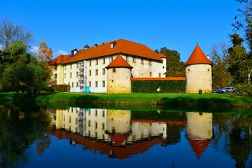 Fototapeta premium View of Otočec castle with a reflection in the water of Krka river in Dolenjska, Slovenia